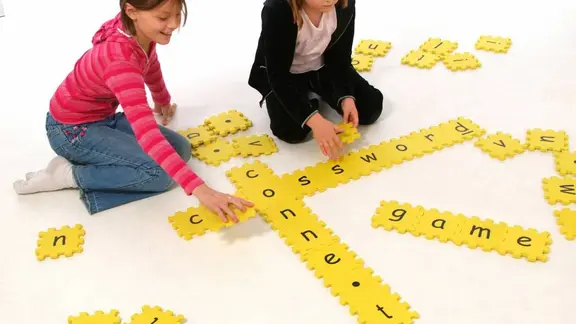 2 kinderen spelen met een scrabble puzzelmat